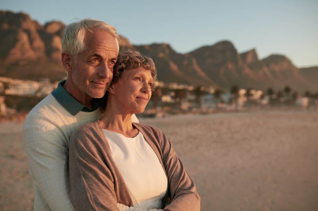Elderly couple standing together and embracing on the beach
